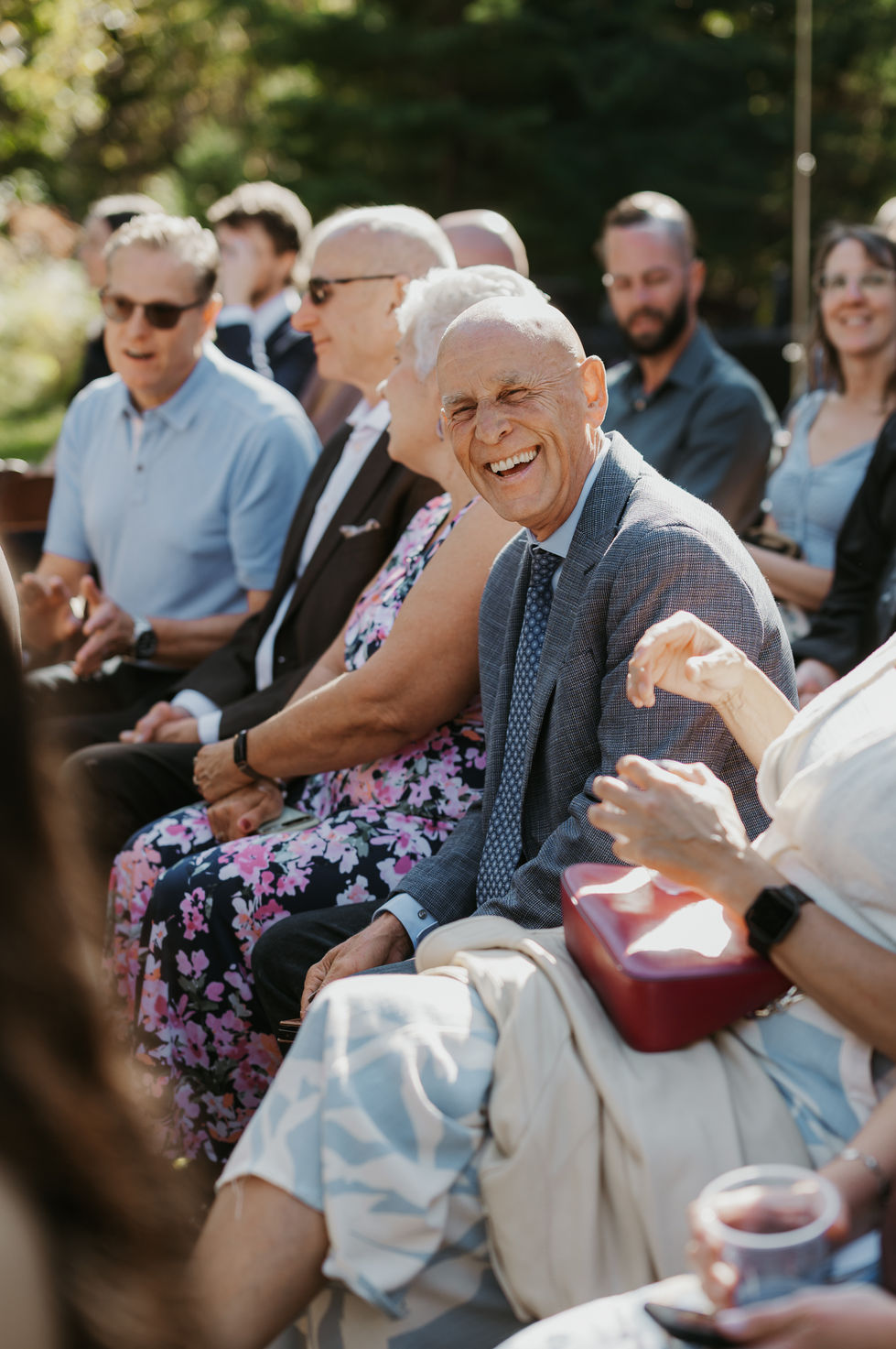 Smiling wedding guests watching an outdoor ceremony at The Valley wedding venue in Alberta.