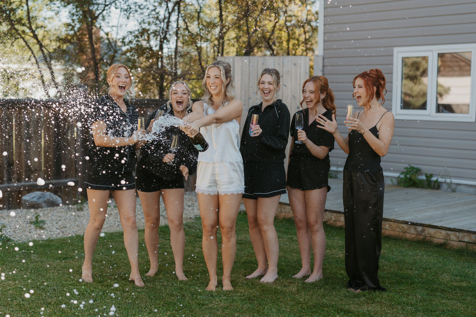 Bride and bridesmaids celebrating together before an Alberta woodland wedding at The Valley.