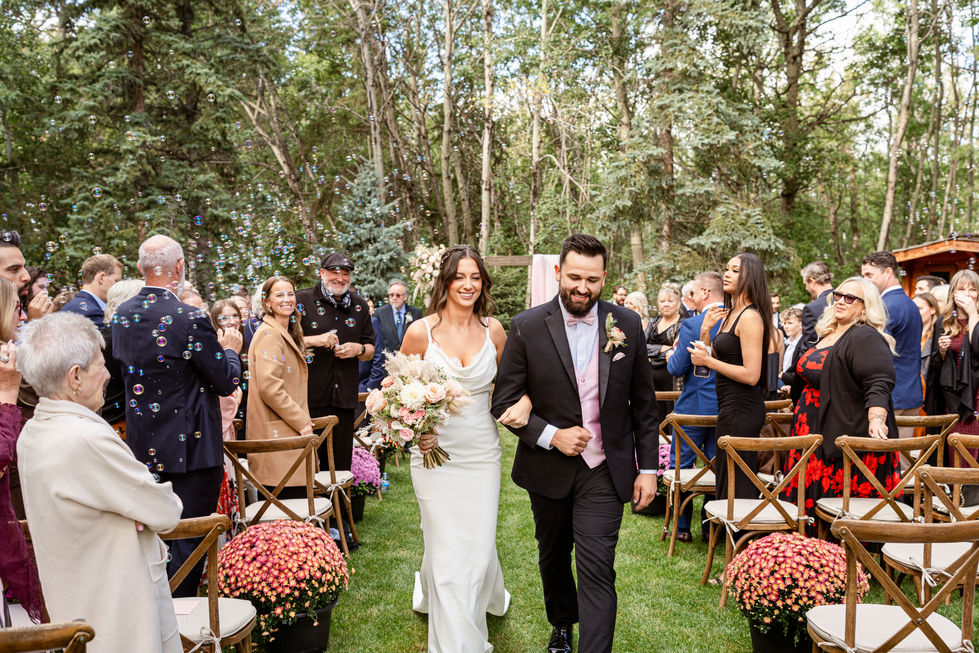 Newlywed couple walking up the aisle after their outdoor backyard wedding ceremony in Edmonton.
