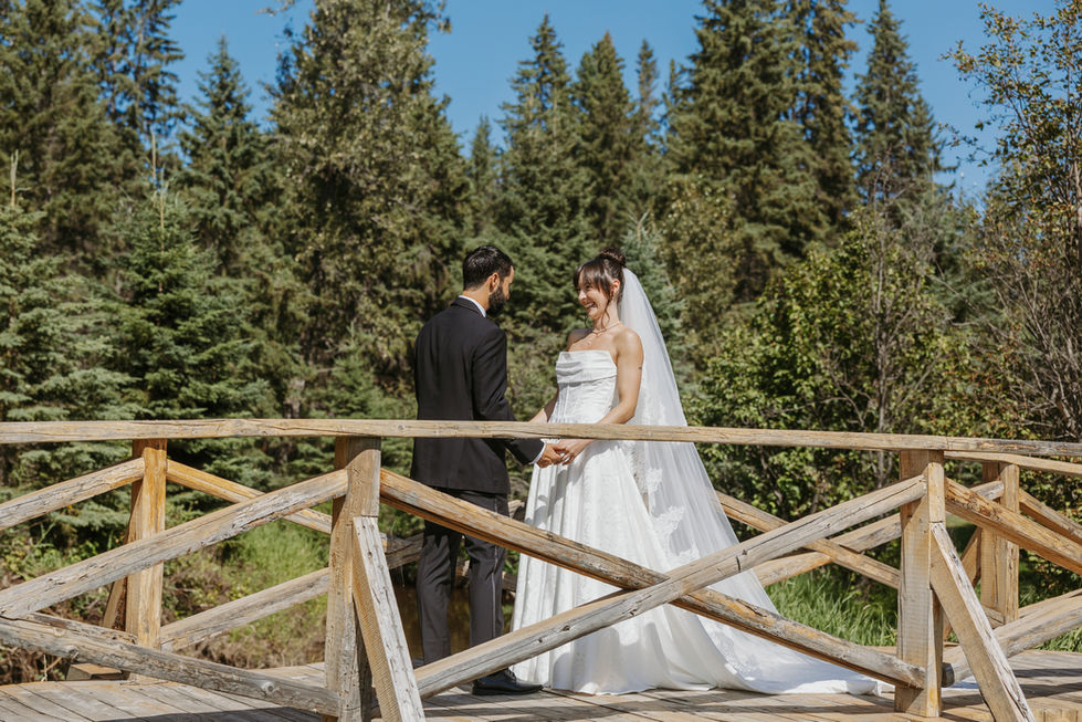 Bride and groom seeing each other during their first look on a wooden bridge at The Valley.