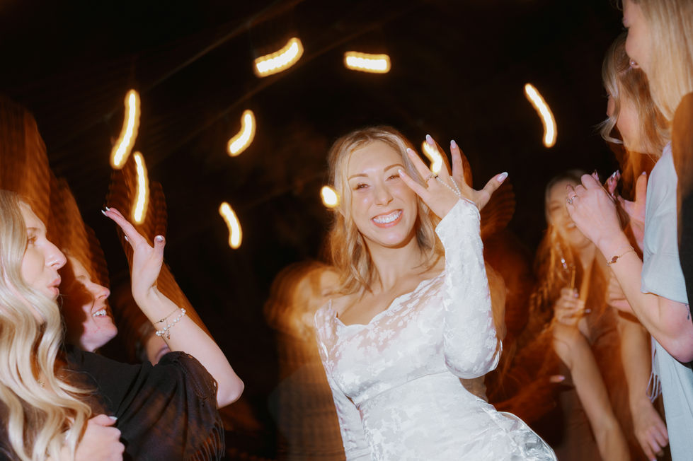 Bride smiling and dancing with friends during her evening wedding reception at The Valley.