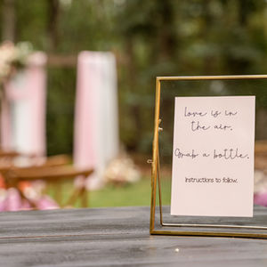 Framed ceremony sign with pink florals at an intimate backyard wedding in Edmonton, Alberta.