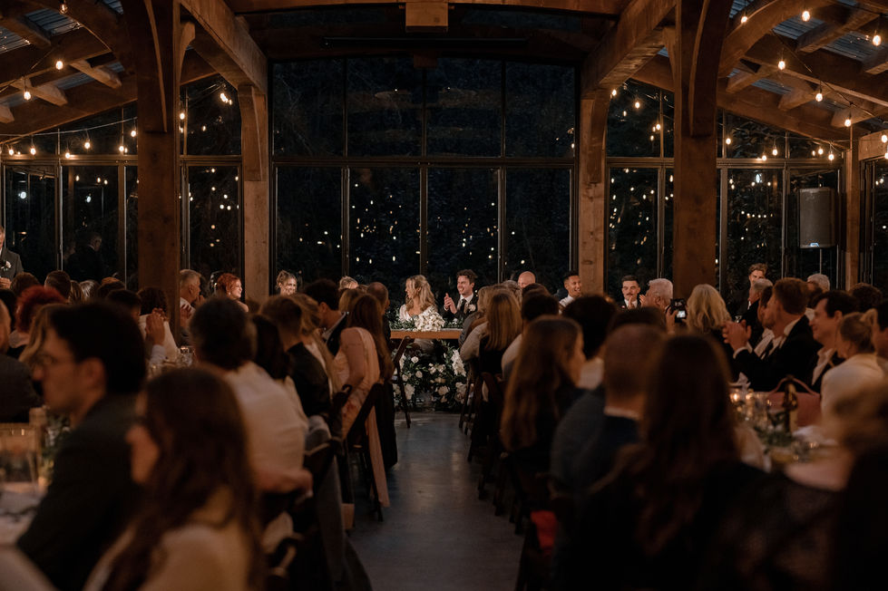 Evening wedding reception with guests seated at long wooden tables beneath string lights at The Valley.
