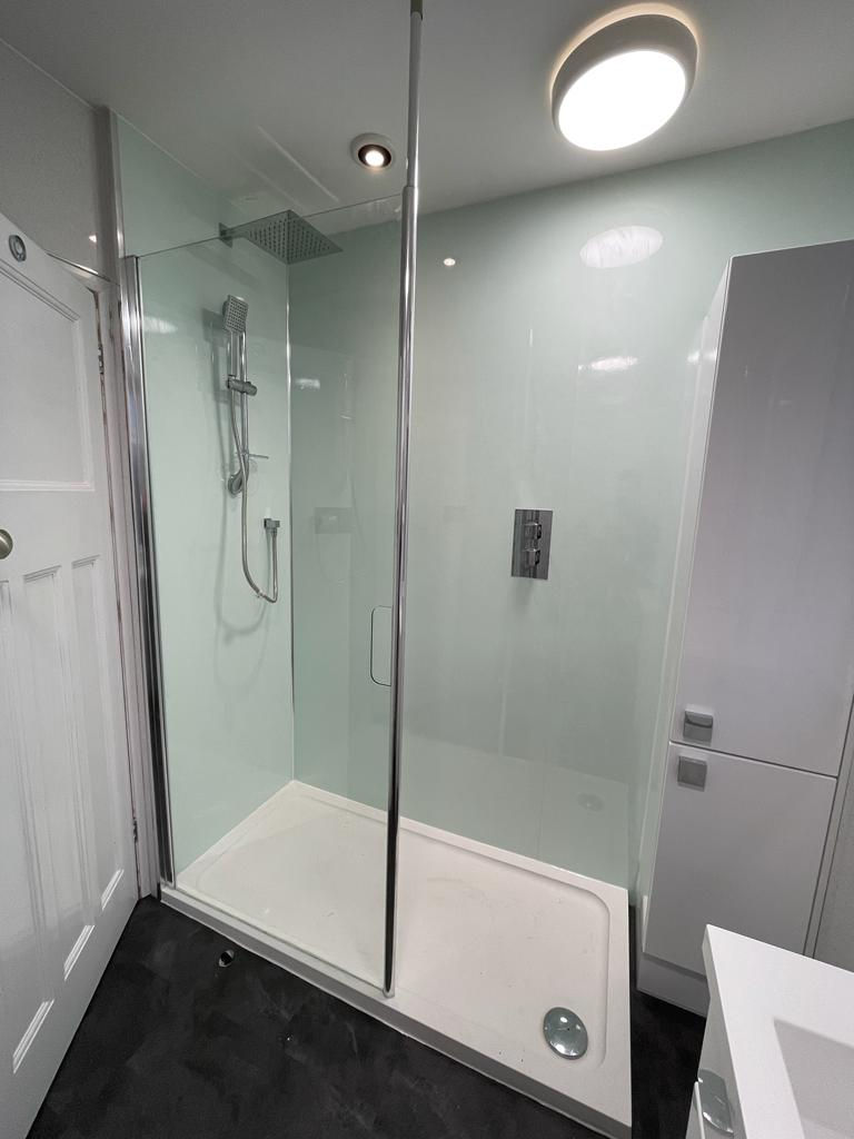 Walk in shower with chrome fittings and a glossy bathroom tall unit for lots of storage.