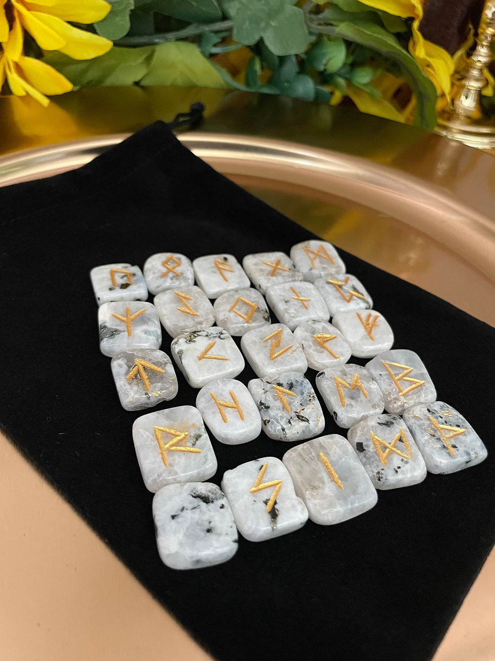 Rainbow Moonstone rune stones with gold-colored runic symbols displayed on a black reading cloth.