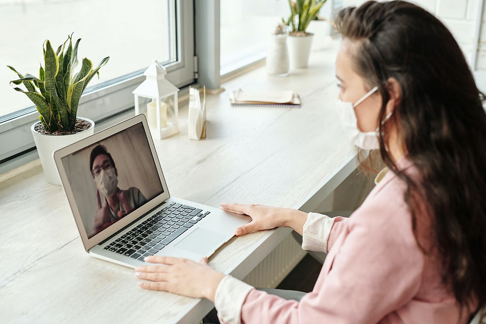 a woman wearing a face mask talking to a man virtually