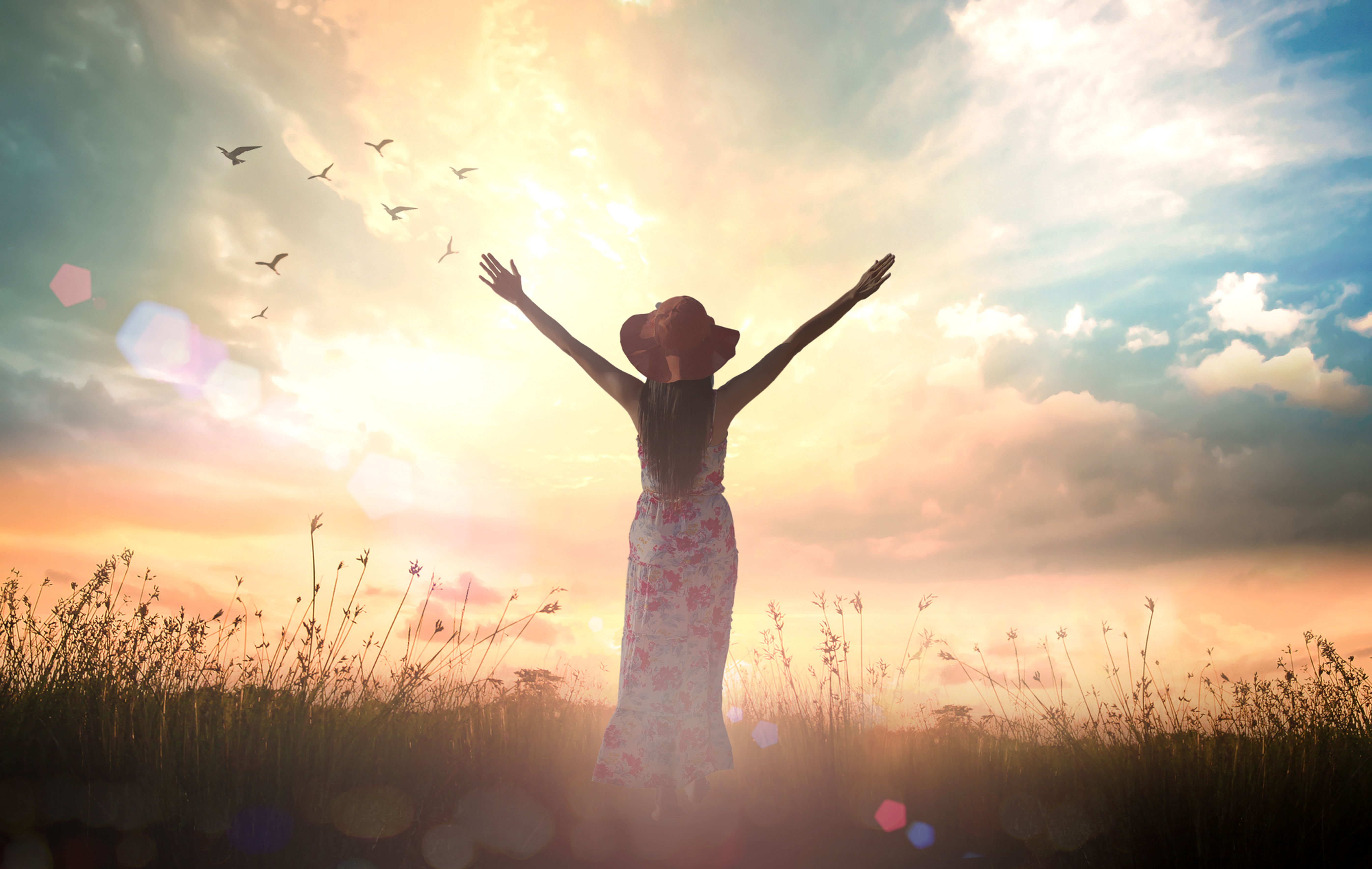 Woman in field with hands raised to God