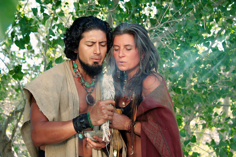 Man and woman in shamanic practice blowing on a smudge stick