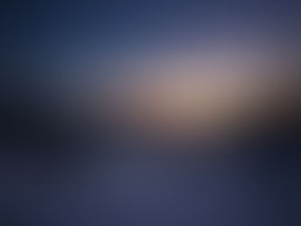 A serene winter night at Lake Michigan, with the tranquil waters reflecting the soft glow of the horizon, framed by snow-covered banks and silhouetted trees under a starlit sky.