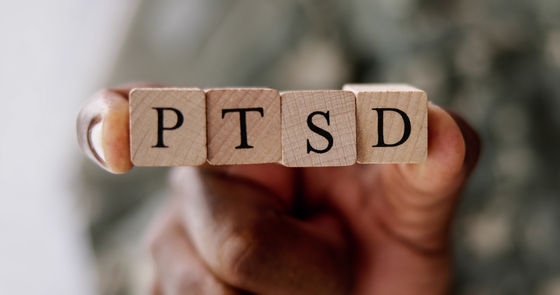 Hand holding wooden blocks spelling out PTSD, highlighting awareness and understanding of Post-Traumatic Stress Disorder.