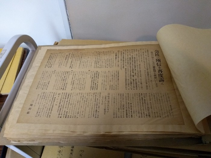 A large pamphlet coverd in Japanese text. The pamphlet is stuck to a volume that is bound on the left.