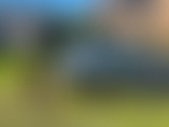 An OHME ePod EV charger mounted on a black pedestal on a grass verge, shown charging a grey Fiat 500e with a yellow charging cable. The installation is situated next to a paved parking bay in front of residential brick properties in Frodsham.