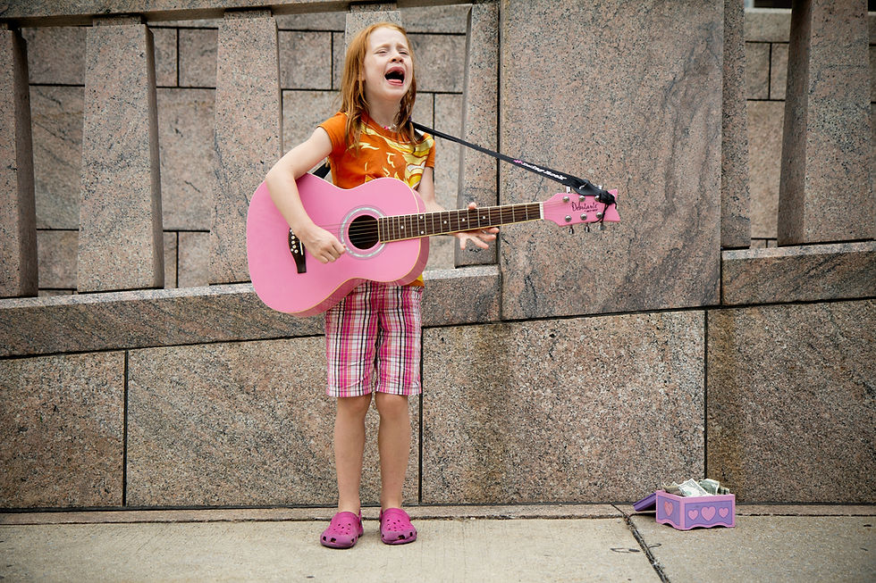 Young voice student singing passionately while playing a pink acoustic guitar, demonstrating the confidence, stage presence, and vocal skills developed through voice lessons at Kingwood Arts Academy of Music, Kingwood, Tx.