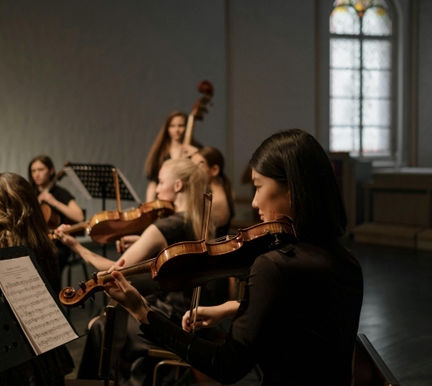 String ensemble students playing violins and cello during a group rehearsal at Kingwood Arts Academy of Music in Kingwood, TX, showcasing collaborative music-making and orchestral skill development.