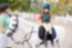 Little boy sitting sideways on a white pony