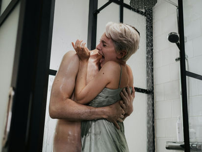 A couple shares a joyful and intimate moment under the shower, embracing with laughter and affection.