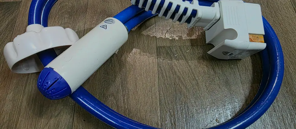Coiled blue and white whale water pump with connectors on wooden floor. No text visible. Calm, organized setting.
