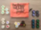 Hexagonal game pieces with insect designs are arranged on a wooden surface. An orange "Hive pocket" bag is in the center.