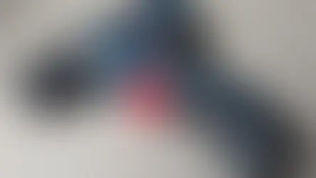 Blue Bosch cordless drill with a red trigger on a light grey surface. Text on drill includes Bosch branding and model info.