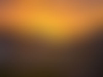 Campers and cars parked by a serene lake at sunset. Mountains silhouette the horizon, with a vibrant orange sky setting a peaceful mood.