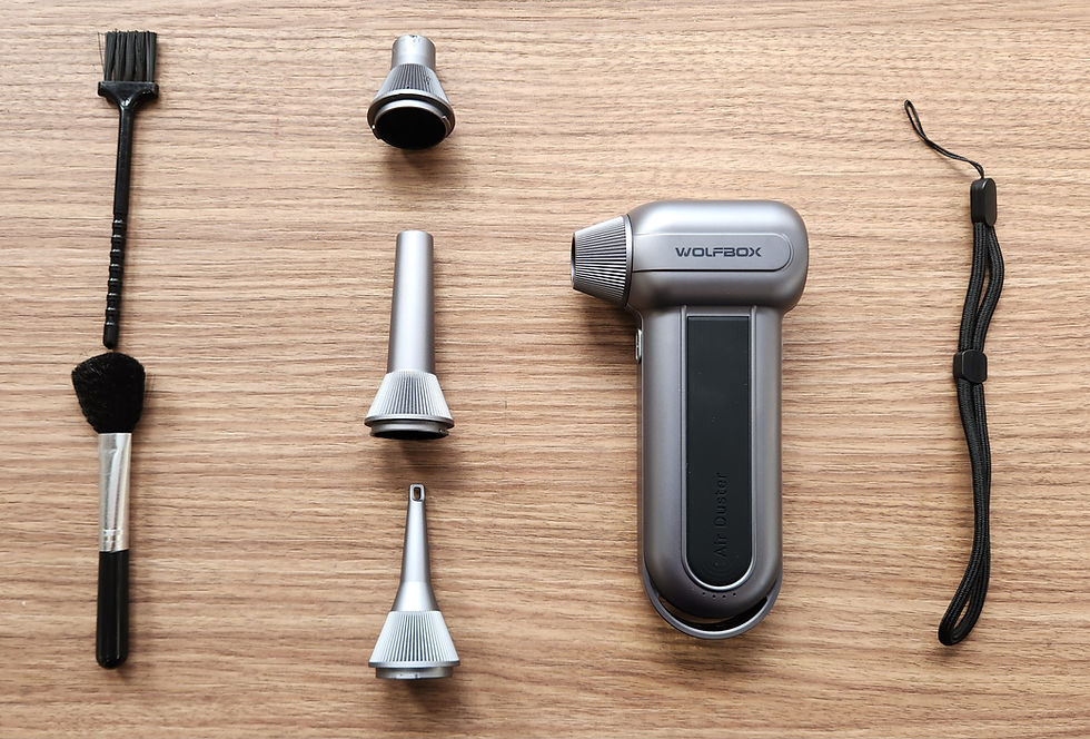 Air duster kit on wood surface: brush, nozzles, air duster labeled "WOLFBOX", and wrist strap. Silver and black colors.