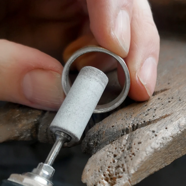 Curving the edges of a silver ring with a file to make it less geometrically shaped