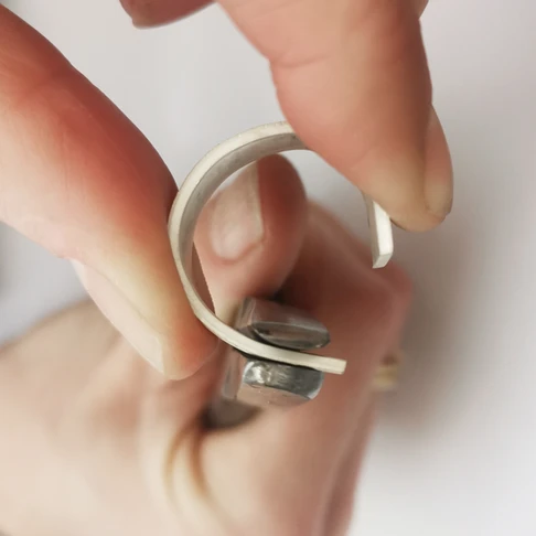 Using pliers to bend a piece of silver into a ring shape