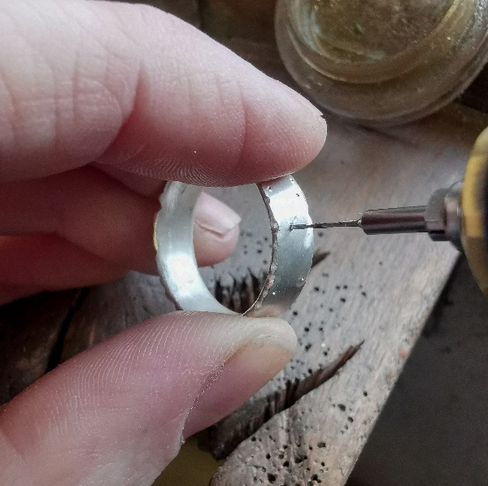 Using different sized drill bits to drill holes in a silver ring