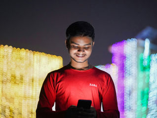 A young Indian man looking at his phone smiling