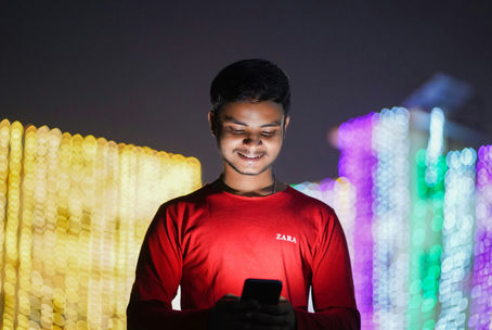 A young Indian man looking at his phone smiling
