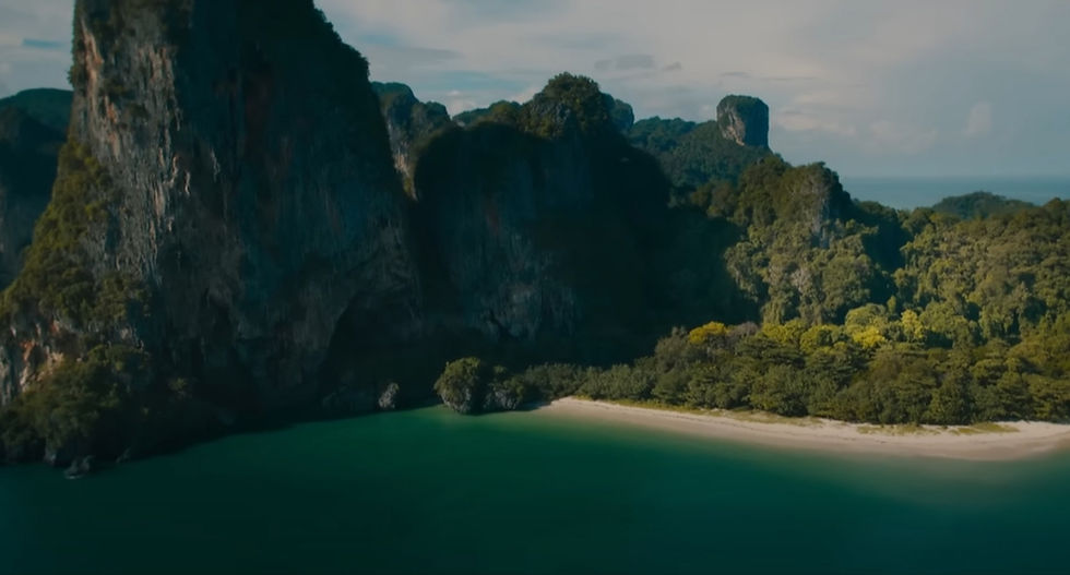 ภาพมุมสูงของหาดซันเซ็ทบนเกาะกระดาน จังหวัดตรัง ชายหาดสีขาวเงียบสงบ รายล้อมด้วยป่าทึบและหน้าผาหินปูน หนึ่งในฉากปิดท้ายของภาพยนตร์ Jurassic World: Rebirth