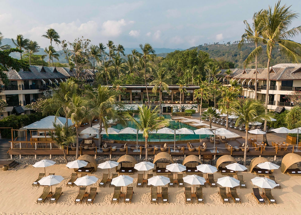 Frontal view of Anantara Bophut Koh Samui Resort with beachfront pool and rows of white sun umbrellas facing the sea.
