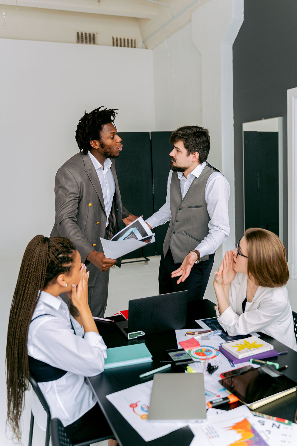 Colleagues engaged in a lively discussion around a workspace table, focusing on conflict resolution