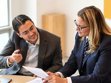 picture of a professional sitting next to another professional who is giving feedback on a
