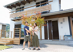 白い外壁の2階建て住宅と家族