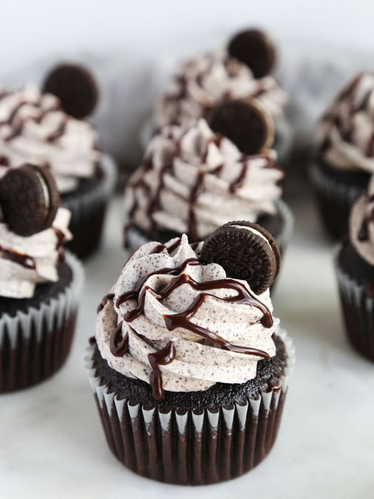 Delicious chocolate cupcakes with frosting and cookie decorations on a tray