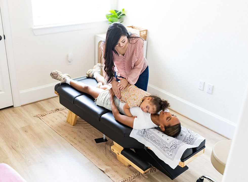 Dr. Tran giving a child a chiropractic adjustment while the child is laying on their mother