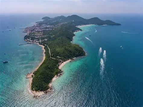Wide angle view of Pattaya beach with clear blue water and sunbathers