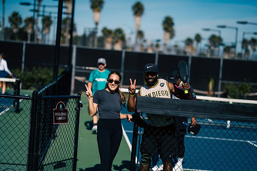 Two smiling pickleball players celebrating a win on a local San Diego court.