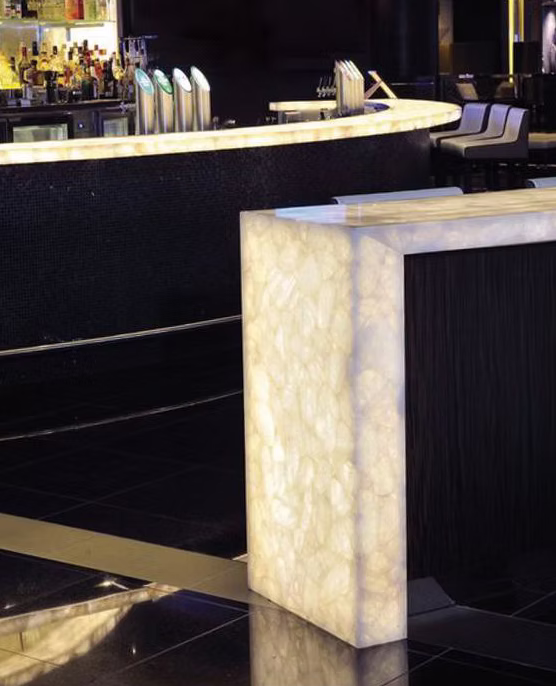 Светящийся бар с барной столешницей из белого кварцита и подсвечиваемой стеной.