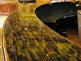 Curved luxury bar counter topped with polished Duramica blue and yellow tiger's eye gemstone slab