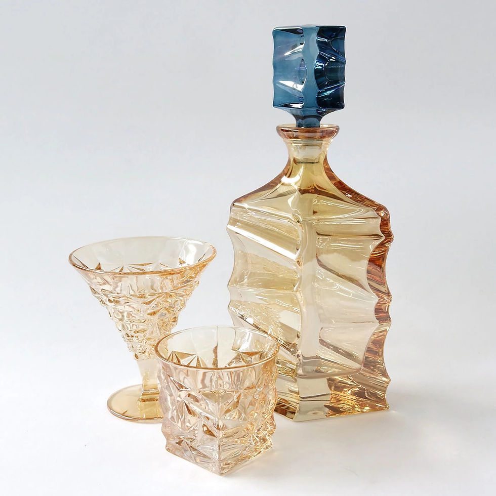 Amber crystal bottle with blue stopper displayed next to matching amber cocktail and whiskey glasses.
