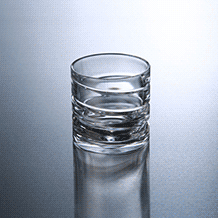 Single crystal spinning shot glass with horizontal textured line engraving on a reflective gray background