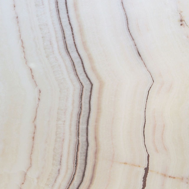 When choosing between natural White Onyx and White Quartz for interior design, understanding their distinct characteristics is crucial. While both offer elegance and versatility, they differ in composition, durability, and maintenance.    Onyx consists of large, solid slabs that are meticulously processed to create unique and large panels. Quartz, on the other hand, is more commonly found in smaller sizes in nature. Each stone is individually processed: it is carefully cut, polished, and treated. Then, they are manually assembled into Duramica panels, filled with special compounds, and undergo technological treatments and polishing. Thanks to Duramica technology, quartz can be assembled into large panels, creating durable and striking products.    White Onyx: Translucent Luxury with a Delicate Touch  White Onyx is a natural stone admired for its translucent beauty and unique veining. Its ability to be backlit makes it a premium choice for feature walls, countertops, and decorative panels.