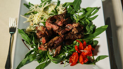 Filete de ternera con tomates cherry sobre plato de rúcula