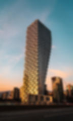 A full shot of Vancouver House in Vancouver with the sunset and clear blue sky in the background