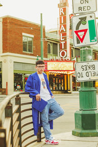 Urban vibe meets graduation style with senior leaning near the Rialto Theatre in cap and gown.