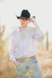 Senior boy adjusting his hat with desert cacti in the background during his Desert Photoshoot in Tucson.