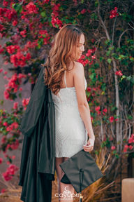 Brenda facing away in a black gown, with pink flowers in the background, radiating elegance.