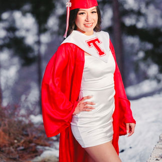 1. Jasmin wearing her red graduation cap and gown, standing in the snow with a confident smile and a blurred forest background.